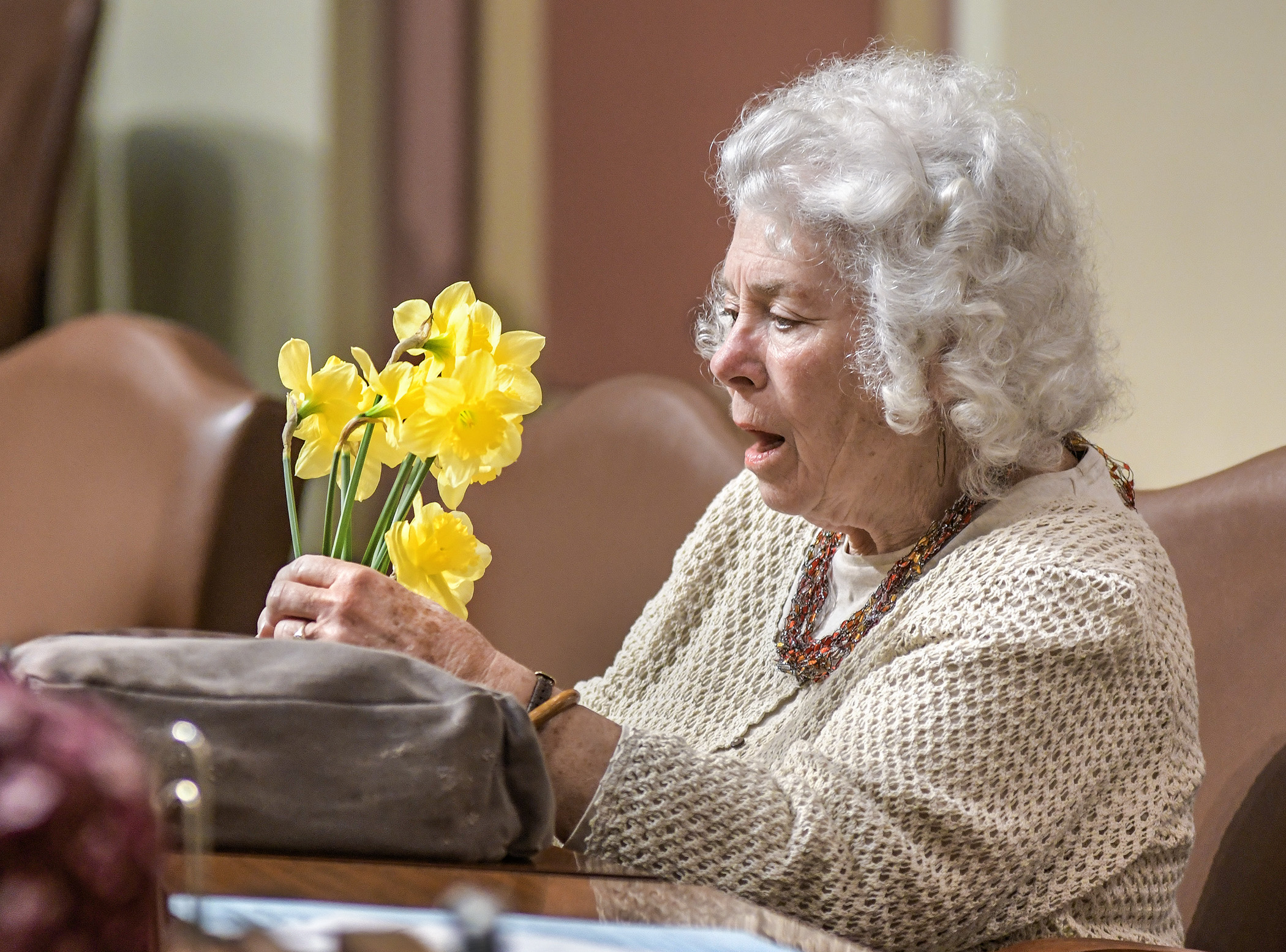 Representative Murphy sits at her desk in the House Chamber and arranges daffodils.